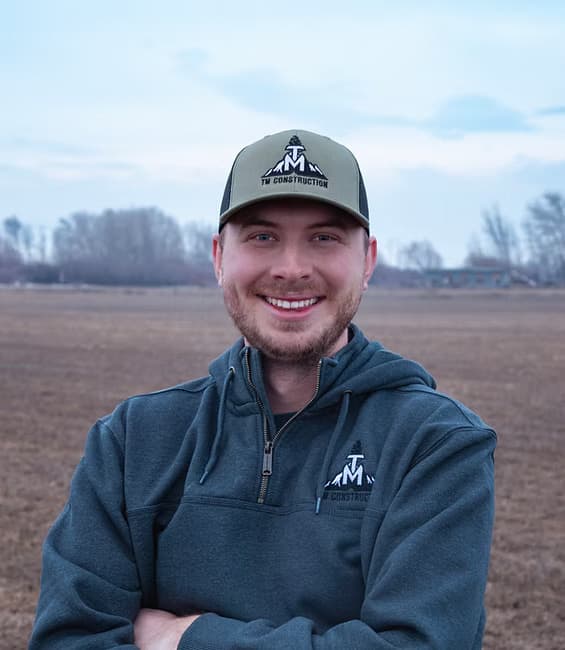 Henry Thomas, Co-Owner of TM Construction, arms crossed in a TM cap and hoodie