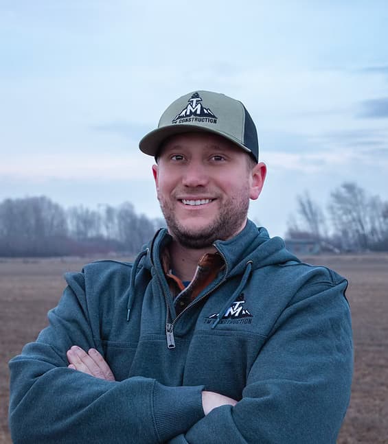 Troy Morris, Co-Owner of TM Construction, arms crossed in a TM cap and hoodie